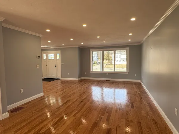 a view of an empty room with wooden floor and a window