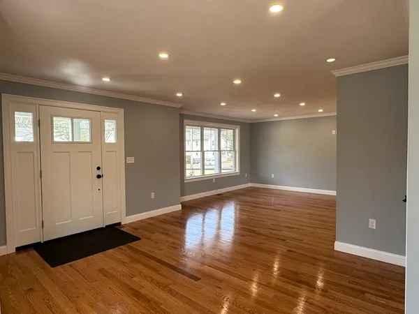 a view of an empty room with wooden floor and a window