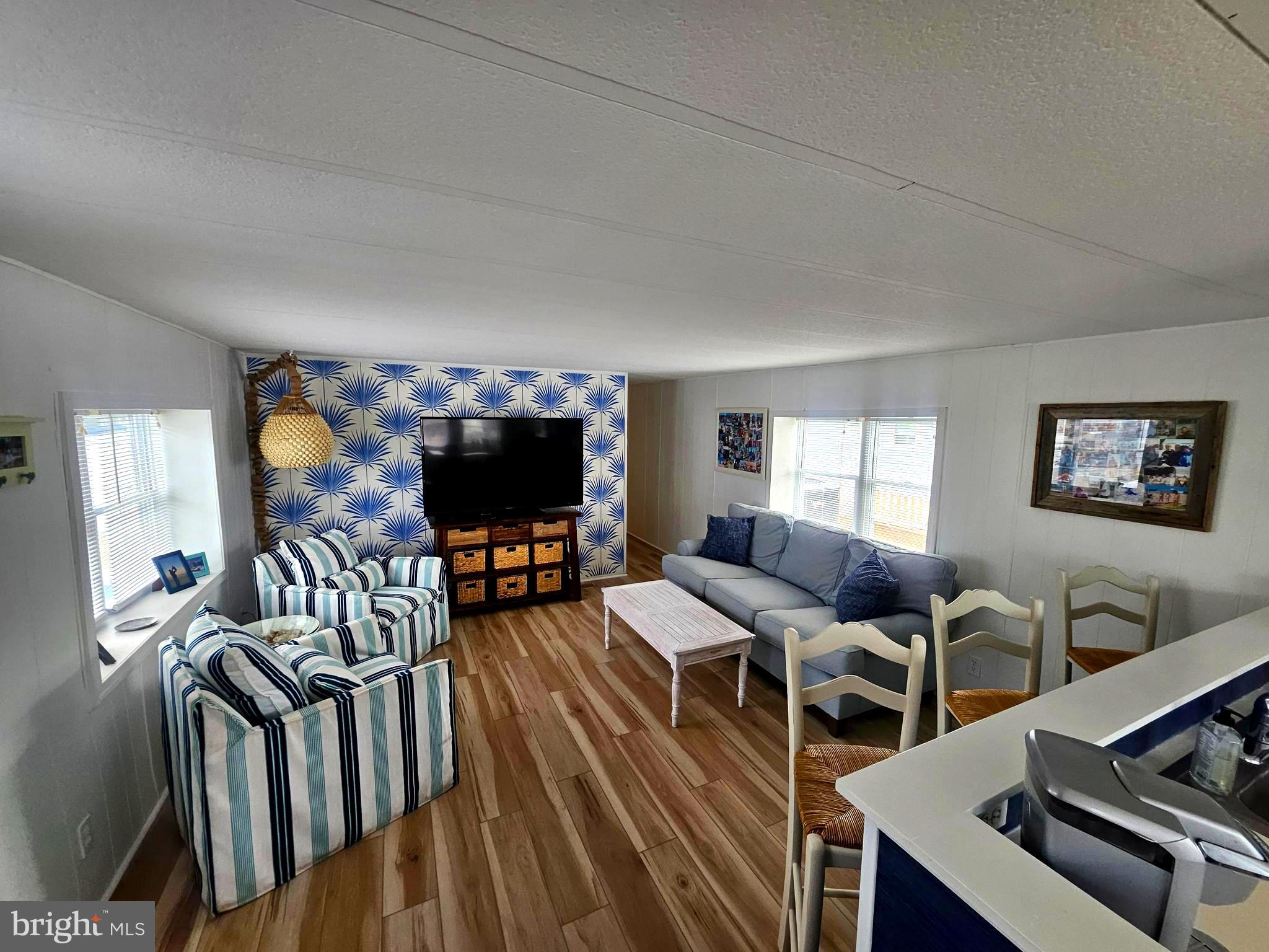 160 Clamshell Road Ocean City, MD 21842 - Photo 5 of 32 a living room with furniture a flat screen tv and a floor to ceiling window