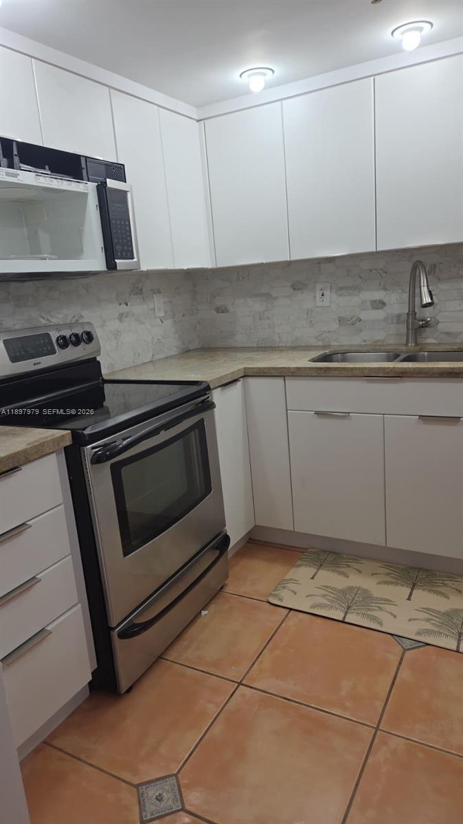 5249 Northwest 7th Street, Unit 418 Miami, FL 33126 - Photo 8 of 25 a kitchen with granite countertop a stove a sink and a white cabinets