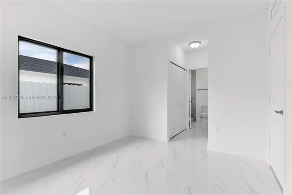 an empty room with mirror and a window