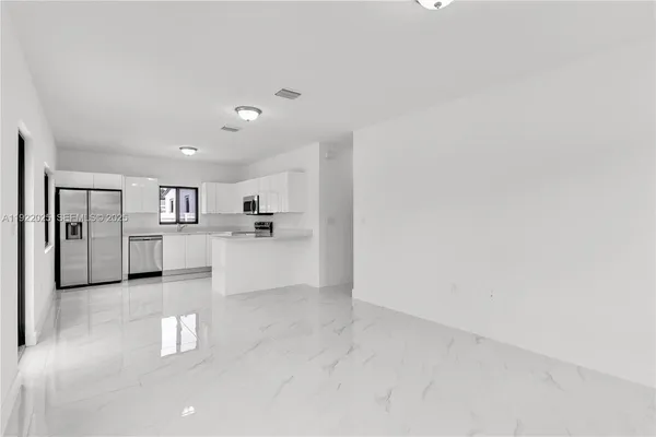 a view of a kitchen with refrigerator and windows