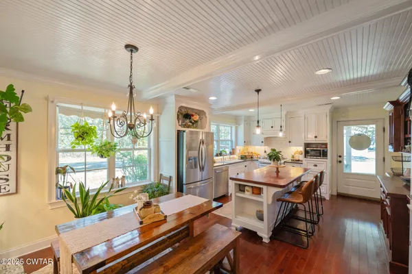 a view of a dining room and livingroom with furniture wooden floor a chandelier