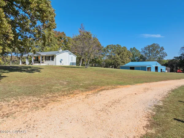 a view of large trees with yard in front of house