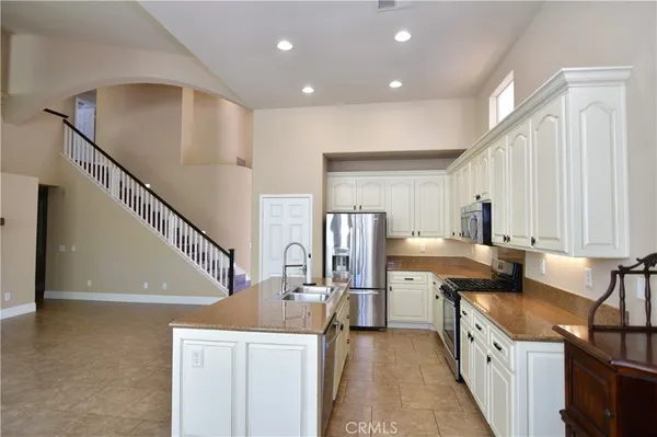 a kitchen with granite countertop a sink a stove top oven and refrigerator