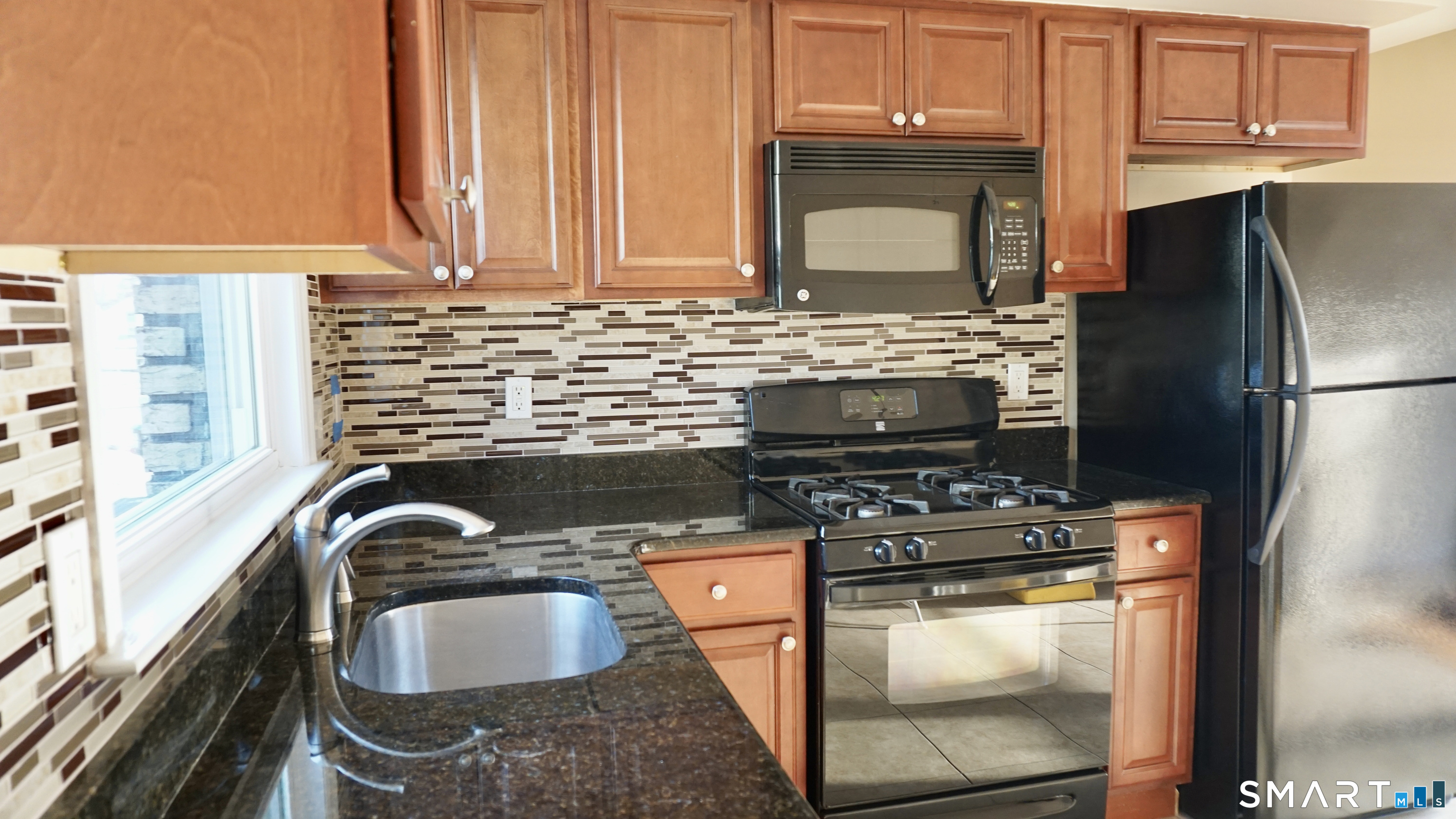 a kitchen with granite countertop a sink a stove and a microwave