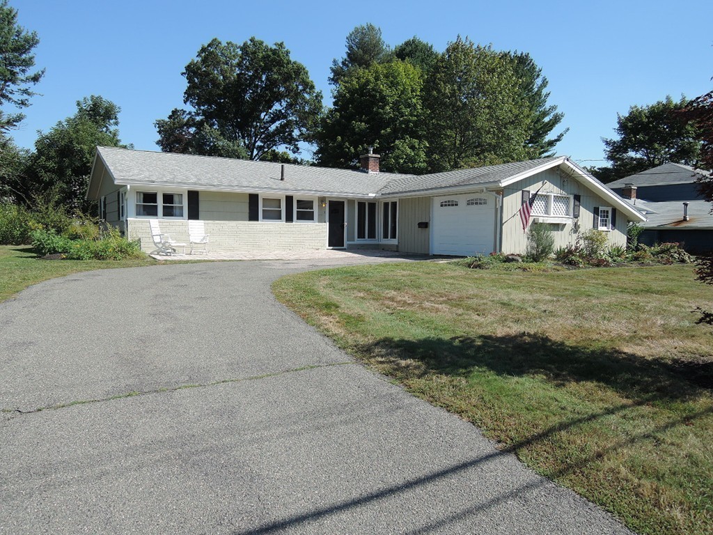 a front view of a house with a garden and trees