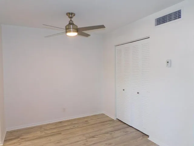 a view of empty room with wooden floor and ceiling fan