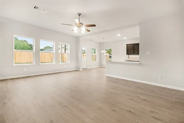 a view of an empty room with a window and wooden floor