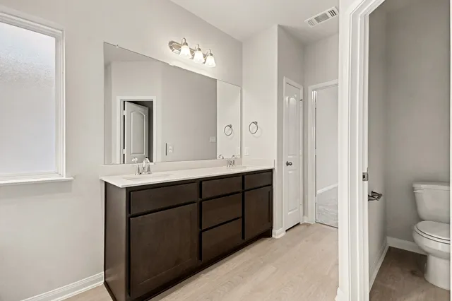 a bathroom with a double vanity sink mirror and toilet