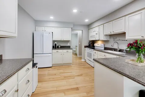 a kitchen with stainless steel appliances granite countertop a sink a stove a refrigerator and cabinets