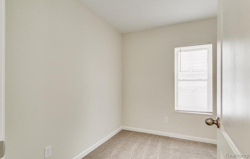 2365 Welch Road Walled Lake, MI 48390 - Photo 10 of 14 Neutral-toned room featuring a single window with blinds, light beige walls, and tan carpet flooring