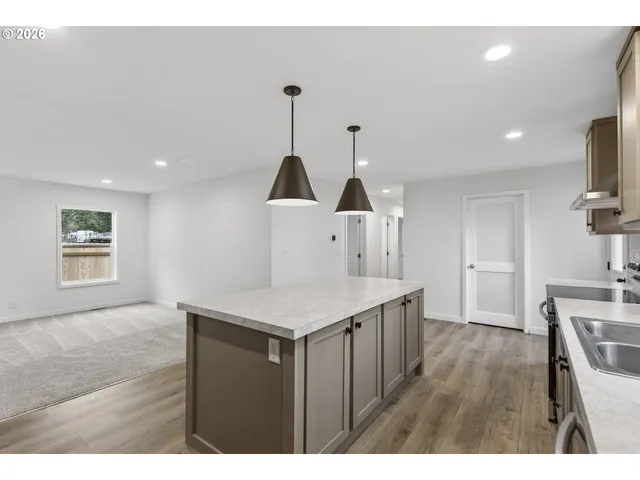 a kitchen with a sink a wooden floor and white cabinets