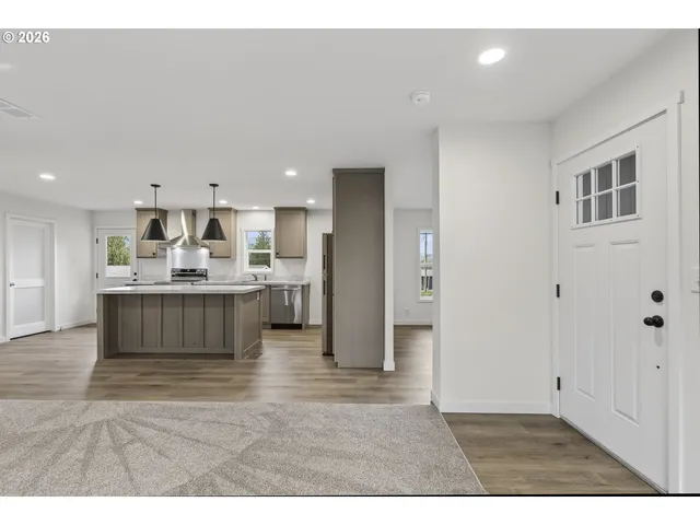 a living room with a kitchen island a sink a stove and a refrigerator