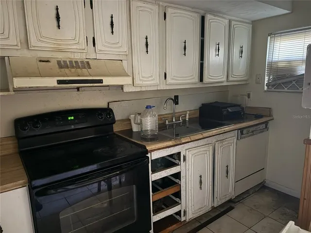 a kitchen with stainless steel appliances granite countertop white cabinets and black stove top oven with granite countertops