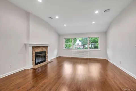 an empty room with wooden floor fireplace and windows
