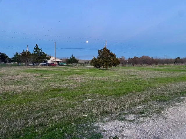 a view of a field with a house in background