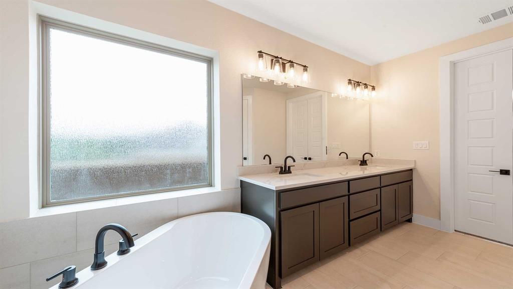 854 Stoney Bridge Way Lavon, TX 75166 - Photo 14 of 36 a bathroom with a double vanity sink a mirror and a bathtub