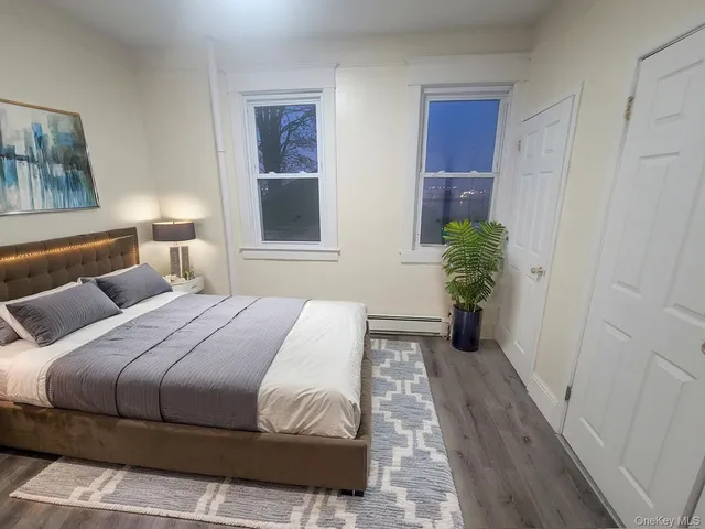 a bedroom with a bed painting on wall and a potted plant