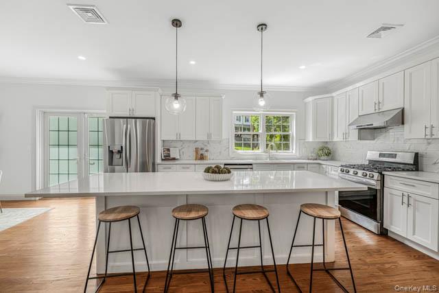 1 Kewanee Road New Rochelle, NY 10804 - Photo 13 of 36 a kitchen with stainless steel appliances granite countertop a stove a sink a oven a dining table and chairs with wooden floor