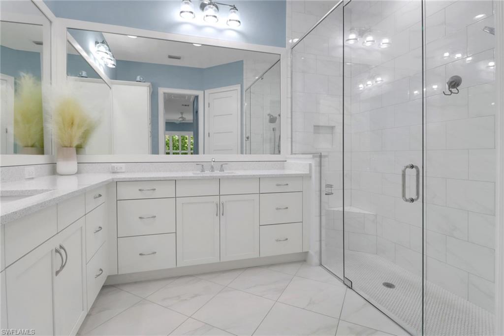 6509 Dominica Drive, Unit 101 Naples, FL 34113 - Photo 14 of 33 a spacious bathroom with a granite countertop sink a mirror and a shower