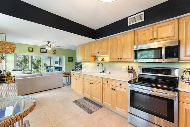 a kitchen with stainless steel appliances kitchen island granite countertop a stove top oven a sink dishwasher and white cabinets with wooden floor
