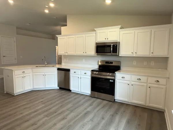 a kitchen with a white cabinets and wooden floor