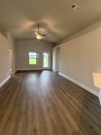 an empty room with windows and ceiling fan