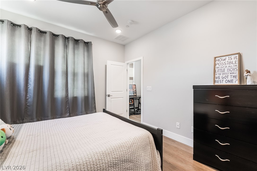 2166 Trivero Street Henderson, NV 89044 - Photo 23 of 61 A comfortable bedroom with rich wood flooring and a modern ceiling fan, offering a tranquil retreat.