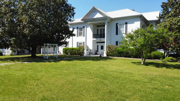 a front view of a house with a yard and trees