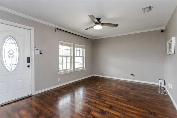 a view of empty room with wooden floor and fan