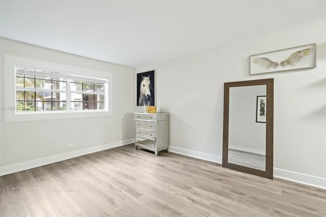 a view of empty room with wooden floor and window