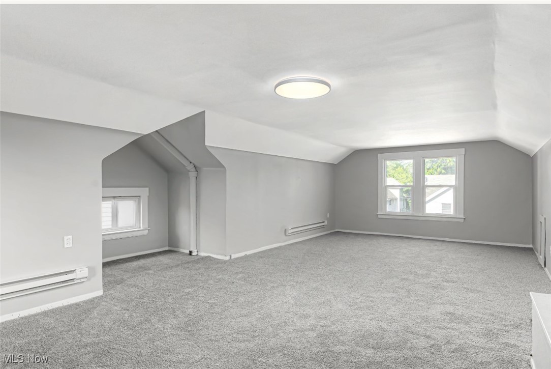 1229 Melbourne Road Cleveland, OH 44112 - Photo 9 of 22 Additional living space with vaulted ceiling, healthy amount of natural light, light colored carpet, and baseboard heating