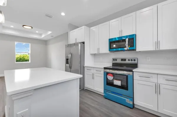 a kitchen with stainless steel appliances a stove a microwave and white cabinets