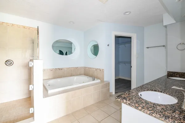 a bathroom with a granite countertop sink a mirror and bathtub