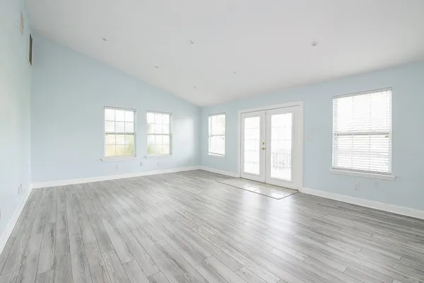 an empty room with wooden floor and windows