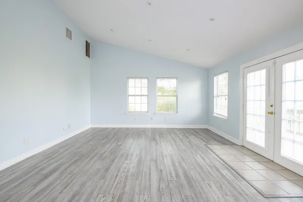an empty room with wooden floor and windows