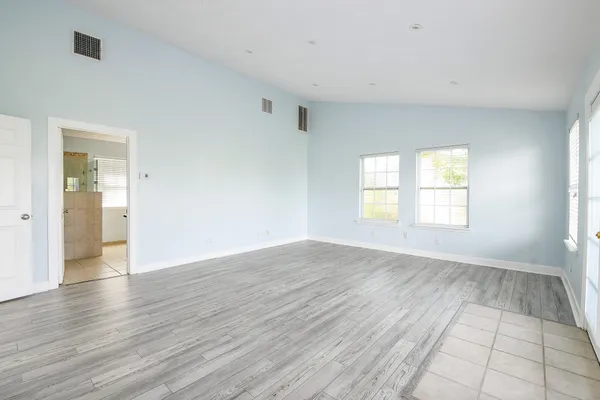 an empty room with wooden floor and windows