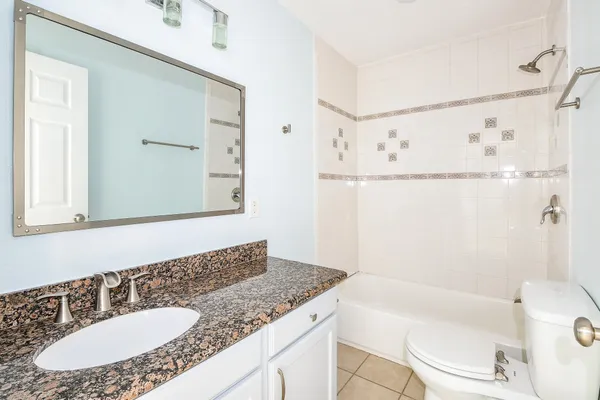 a bathroom with a granite countertop sink a mirror a bathtub and shower