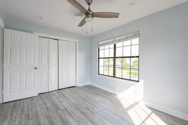 a view of an empty room with a window and wooden floor