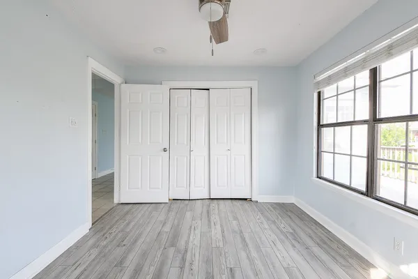 an empty room with wooden floor cabinet and windows
