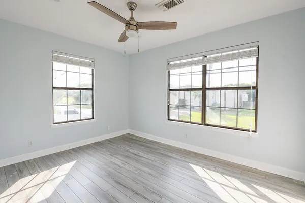 a view of an empty room with wooden floor and a window