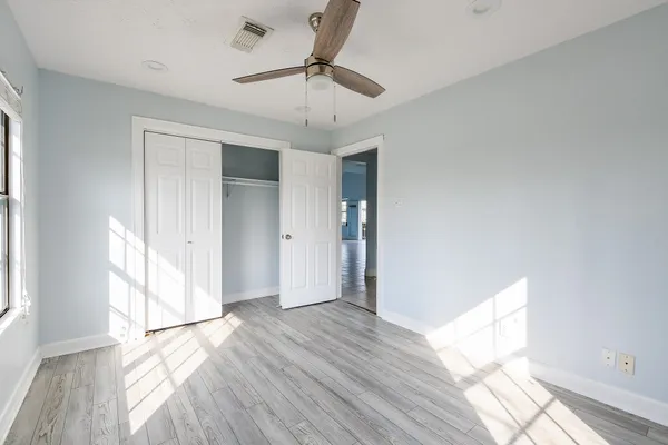 a view of empty room with wooden floor and fan