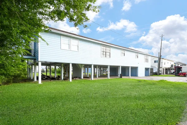 a view of a white house with a big yard and large trees