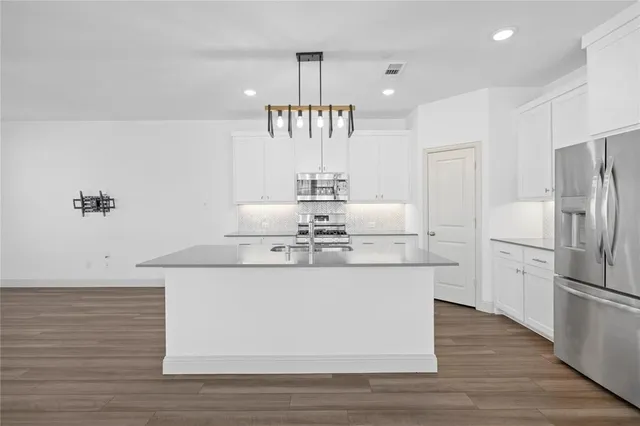 a kitchen with kitchen island stainless steel appliances a sink and a refrigerator