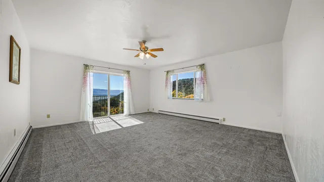 an empty room with windows and ceiling fan