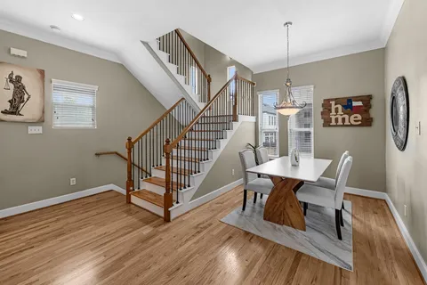 a kitchen with stainless steel appliances granite countertop a stove top oven a sink dishwasher a refrigerator and a dining table with wooden floor