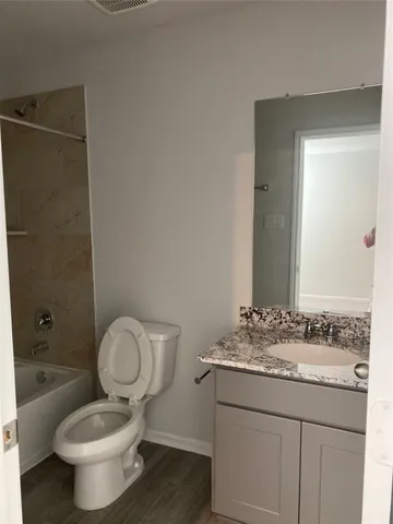 a bathroom with a granite countertop toilet sink and mirror