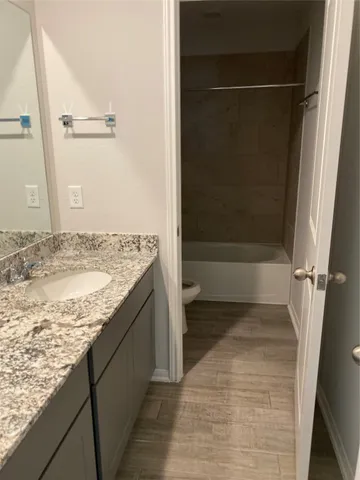 a bathroom with a granite countertop sink a toilet and shower