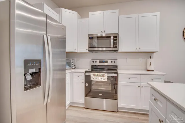 a kitchen with stainless steel appliances white cabinets and a refrigerator